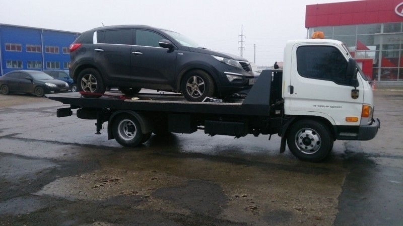 Изображение черной машины, погруженной на эвакуатор.